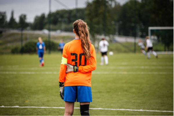 Girl goalkeeper looking at football pitch Girl goalkeeper looking at football pitch